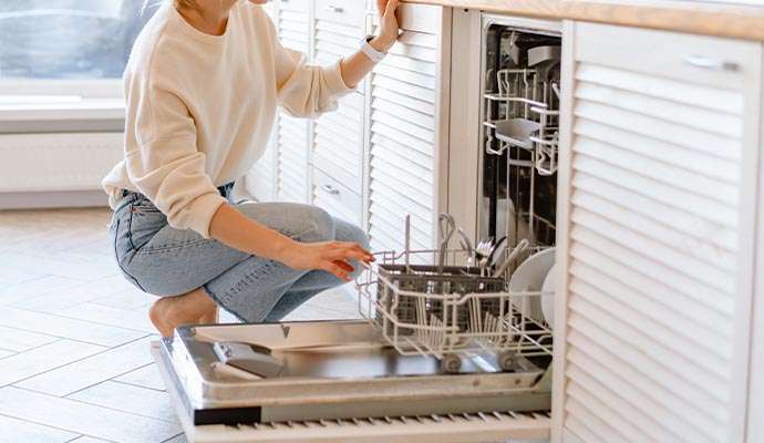 A woman is cleaning the dishwasher